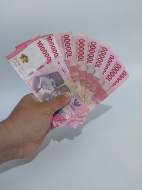Endonezya rupiası taşıyan bir adam, yüz bin rupiah.