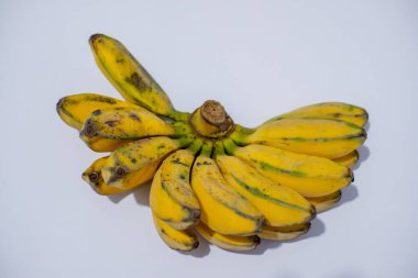 Sarı renkli muz ve beyaz arkaplanda yeşil yapraklar.