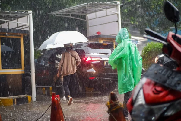 Şiddetli Yağmur sahnesinde insanlar şemsiyelerle dışarı çıkıyorlar.