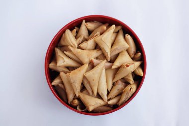 Kırmızı kenarlı bir kase samosa ve siyah bir kase.