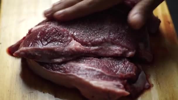 黒い背景に木製のプレートに生のステーキ — ストック動画