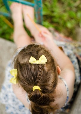 At kuyruklu ve sarı kurdeleli bir kız kurabiye yer. Yakın çekim, üst manzara. Küçük bir kız bahçedeki köyde saman kurabiyesi yiyor, yakın plan..