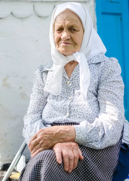一个老妇人的画像 一位90岁的妇女笑着坐在房子旁边 乌克兰老年妇女 乌克兰村民 — 图库照片