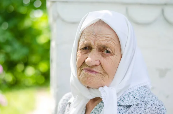 stock image Portrait of an old woman. A woman (90 years old) smiles and sits near the house. Ukrainian senior woman, Ukrainian village.Outdoor