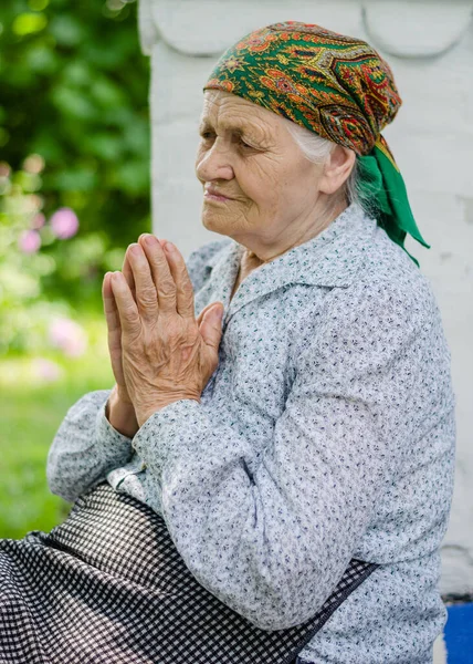 Ukrainian senior woman  prays. Old age, loneliness. Russian aggression against Ukraine. old christian woman.