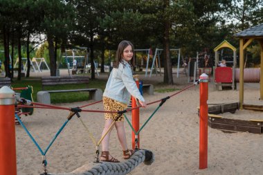 Çocuk parkında mutlu bir kız. Kız ağ iplerinde oynuyor..