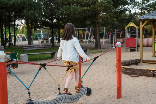 stock image A happy girl at a playground. The girl is playing on net ropes.