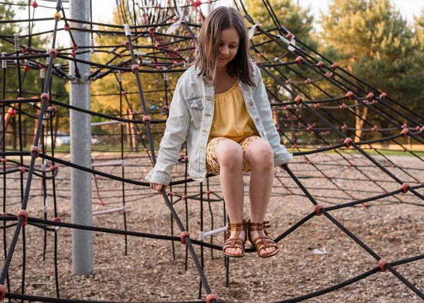 stock image A happy girl at a playground. The girl is playing on net ropes.