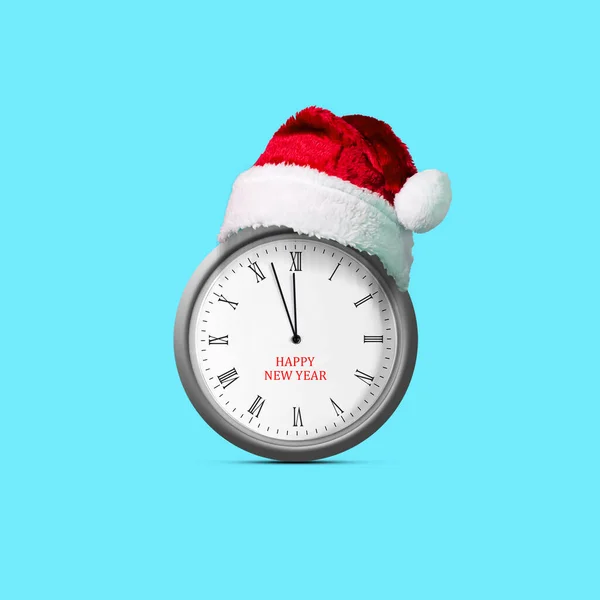 Clock in a Santa Claus hat. Isolated on blue background. Design element. Christmas background. Festive background.