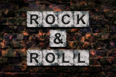 Rock and Roll. Words on stone blocks, on old vintage bricks wall. Direction in music. Musical style. Design element.