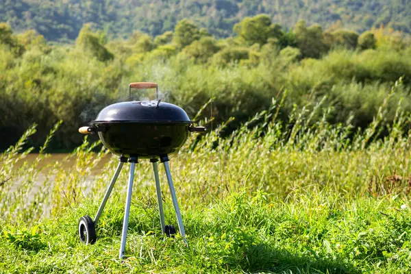 Barbecue, charcoal grill on the river bank. Relaxation, cooking in the fresh air. Summer rest. Background.