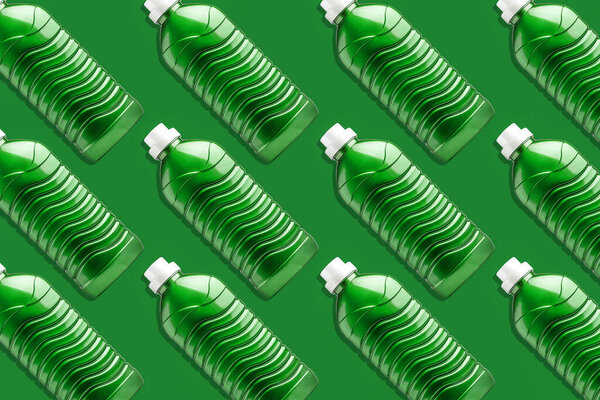 Много зеленых пластиковых бутылок для мытья геля, жидкого моющего средства, отбеливателя и смягчителя ткани, на зеленом фоне. Фон