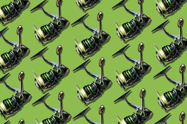 Lot of Reels for spinning fishing on a green background. Fishing equipment. Fishing background.
