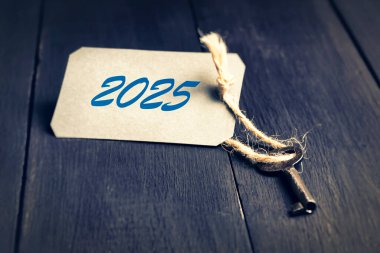 Üzerinde 2025 yazan anahtar, koyu mavi ahşap masa. Yeni yıl geçmişi. Tatil arkaplanı.