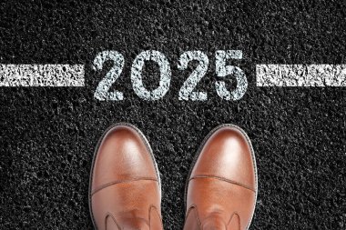 2025 geliyor. Asfalt yolda erkek botları. Yeni yıl için planlar. Yeni yıl konseptinin başlangıcı. Tatiller.