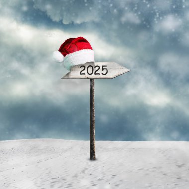 2025 numaralı tahta tabela ve karlı yolda Noel Baba şapkası. Yılbaşı Yılbaşı geçmişi.