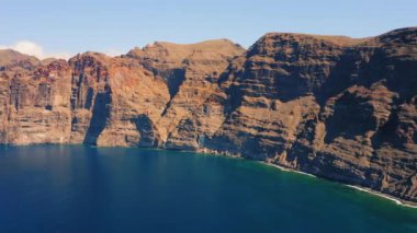 Suyun üzerindeki muhteşem manzara, güzel kahverengi ve kırmızı renkli kayalar. Dalgalar kayalıklara çarpıyor. Okyanusun ortasındaki Tenerife Adası. Dünyayı dolaş. Canlı mavi renkler. Kimse..