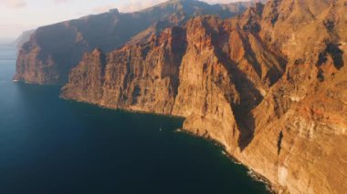 Suyun üzerindeki muhteşem manzara, güzel kahverengi ve kırmızı renkli kayalar. Dalgalar kayalıklara çarpıyor. Okyanusun ortasındaki Tenerife Adası. Dünyayı dolaş. Canlı mavi renkler. Kimse..