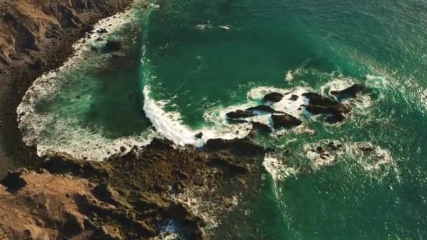 从空中俯瞰着巨大的海浪在空旷的岩石热带海滩上冲撞和发泡 形成了巨大的火山 野生海滩与深蓝色碧水相遇 — 图库视频影像
