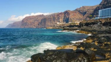 Dev uçurumlar ve Atlantik Okyanusu 'nun havadan çekilmiş görüntüleri Los Gigantes, Tenerife, İspanya. Turist tatil beldesi, yaz tatili. Volkanik kıyı şeridi. Mavi dalgalar sıçradı.