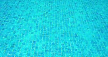 Yüzme havuzunda su dalgalanması. Arka plan mavisi. Alt taraftaki küçük fayanslar. Yakın çekim statik görüntü. Kuyu suyu.