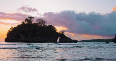 Crystal Bay Beach Nusa Penida arka planda güzel günbatımı. Turuncu ışık su yüzeyine yansıyor. Sakin okyanus dalgaları kumlu kıyıya çarpar. Sabit çekim yavaş çekim. Kimse..