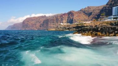 Dev uçurumlar ve Atlantik Okyanusu 'nun havadan çekilmiş görüntüleri Los Gigantes, Tenerife, İspanya. Turist tatil beldesi, yaz tatili. Volkanik kıyı şeridi. Mavi dalgalar sıçradı.