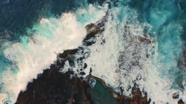Azureの海の波は 水しぶきと白い泡で岩の多い海岸火山の形成でクラッシュします 空中飛行を停止する — ストック動画