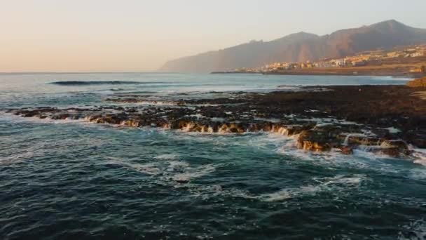 風の強い日に白い泡を形成するロサンゼルスギガンテスの休暇リゾートの紺碧の海ウォッシュビーチの巨大な波 澄んだ青い空の下でかすみで覆われた深い岩の崖は 小さな低上昇の町の上に舞い上がります — ストック動画