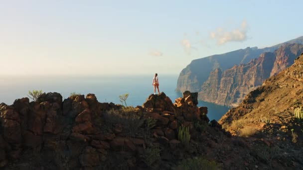 站在山顶上的妇女欣赏着远足于洛斯吉昂斯悬崖峭壁的自然景观 狂欢者的梦想 空中飞越深蓝色的岩石海滩 真正的人在一段时间内旅行 — 图库视频影像