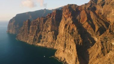 Suyun üzerindeki muhteşem manzara, güzel kahverengi ve kırmızı renkli kayalar. Dalgalar kayalıklara çarpıyor. Okyanusun ortasındaki Tenerife Adası. Dünyayı dolaş. Canlı mavi renkler. Kimse..