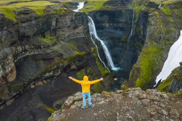 黄色のジャケットを着た男の空中からの眺めは アイスランドの高地の渓谷と滝を楽しんで手を上げます アイスランド — ストック写真