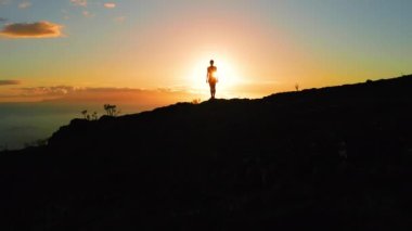 Gün batımında dağın tepesinde bir kadın silueti. Hava aracı. Güneş ışınları insanı benekler. Yürüyüşçü güneşin doğuşunun tadını çıkarıyor. Güneş ışınları okyanustan yükselir. Yalnız kız dikiz aynası.