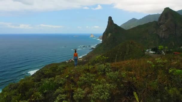 Aerial Woman Stands Cliff Edge Ocean Mountain View Flourishing Green — Stock Video