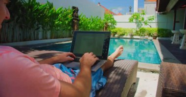 Erkek eller yaz havuzu arka planında dinlenirken dizüstü bilgisayarda klavye yazıyorlar. İş adamı, öğrenci, profesyonel çalışma veya bilgisayar yazılımı kavramı ile çalışma, yakın plan