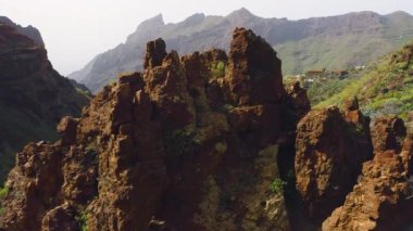 İnsansız hava aracı Teno Ulusal Parkı Masca Vadisi ve köyündeki beyaz sis bulutlarıyla çevrili devasa volkanik yeşil dağların üzerinden uçuyor. Tenerife Kanarya Adaları İspanya Avrupa. Havadan. Rezerv.