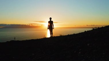 Karanlık, karamsar, doğal dağ uçurumları gece deniz manzarası derin okyanus arka planında yalnız bir kadınla. Hava rengarenk doğa günbatımı. Los Gigantes Tenerife.