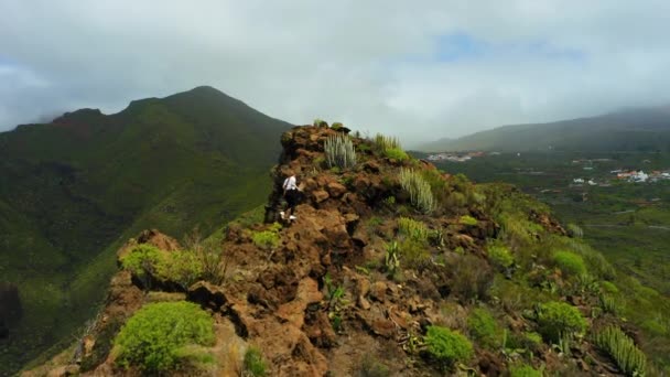 空中のリアビュー女性のハイキングは 山の風景の中に崖の端をクロール登る 観光客は自然火山の自然を楽しみ 彼女の手を上げる 天望国立公園 テネリフェ島カナリア諸島 — ストック動画