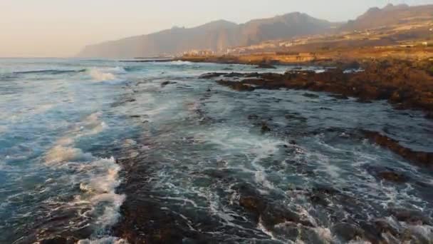 海の水に反射し 岩の多い海岸を照らす柔らかい日没の光 秋の暗い海 岩の上で泡の波がクラッシュします 劇的な性質 — ストック動画