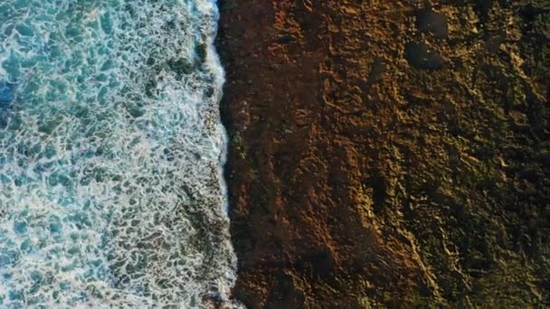 岩だらけの海岸線で海の波の泡の衝突の抽象的な空中ビューの上 ドローンの飛行映像 火山黒ビーチ — ストック動画
