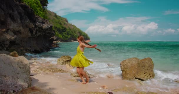 在夏日阳光明媚的沙滩上 跳舞着旋转着跳舞着的快乐快乐的女孩享受着假期 赤脚迷人的女人花时间在海洋上 浪花起泡 微笑的女士在海滨玩得开心 — 图库视频影像