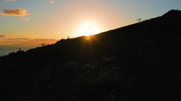 海の夕日の背景に暗い自然景観の山の崖と太陽の光に照らされた少女のシルエット 空中カラフルな空 自然の美しさ ギガンテス テネリフェ 日の出 — ストック動画