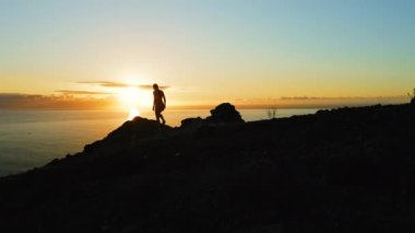 Karanlık, karamsar, doğal dağ uçurumları gece deniz manzarası derin okyanus arka planında yalnız bir kadınla. Hava rengarenk doğa günbatımı. Los Gigantes Tenerife.