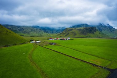 Çevre yolunda İzlanda 'nın güney kıyısının havadan görüntüsü. Gündüzleri İzlanda 'da manzara. İnsansız hava aracı görüntüsü. Yaz. Hava bulutlu. Sahada taze çimenler. Seyahat ve tatil görüntüsü.