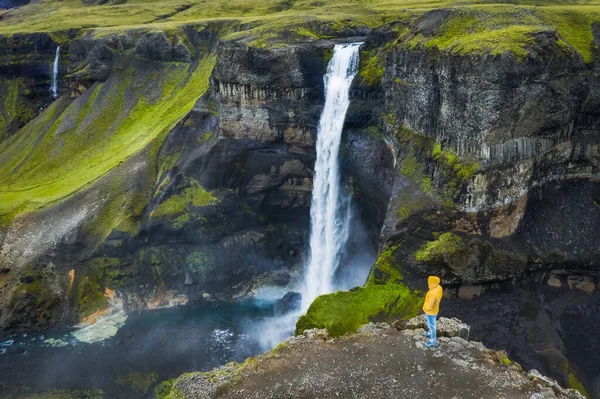 身穿黄色外套的人欣赏冰岛Landmannalaugar峡谷的Haifoss瀑布 空中全景无人驾驶飞机视图 — 图库照片