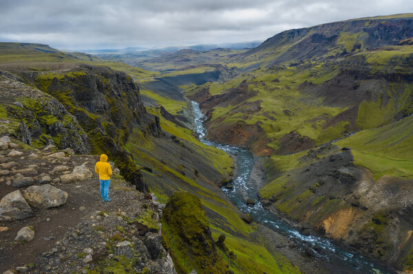 Aerial view of man standing on the cliff edge enjoying Iceland highland valley and Haifoss waterfall.