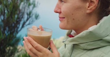 Dağın tepesinde doğa kökenli kahve içen tatmin olmuş bir kadının portresi. Ormanda kapuçino içen çekici bir kız. Sisli bir sabah. Gülen surat. Ağır çekimde yakın çekim. Anaga