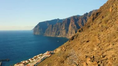 Sunset light illuminate steep Los Gigantes cliifs rocky barren volcanic mountains with dark blue deep ocean water. Sea, crags silhouette. Nature seascape. Paradise island Tenerife. Nobody.