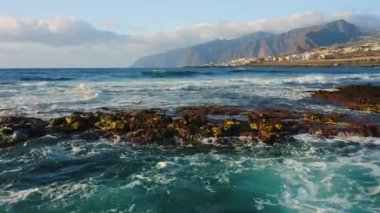 Drone flight close to the ocean waves along the horizon. Aerial view of sea foam and turbulent water. Volcanic black rocky beach of Tenerife Canary Islands Spain Europe. Nobody.