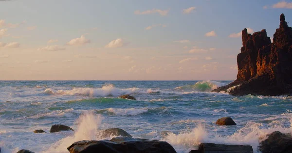 明亮的大海落日 海浪冲向岩石 被温暖的落日 特内里菲岛的火山玄武岩点亮 海浪分解成浪花和白沫 无穷无尽的大自然之美 — 图库照片